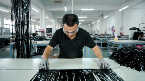 Our workers are in the quality control area using a long ruler to carefully measure the unfolded black metallic foil tinsel curtain, ensuring that the width, length, and fringe uniformity of every batch meet the highest standards and deliver consistent premium quality to our customers.